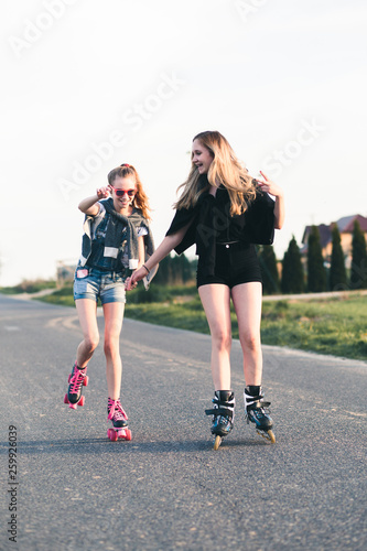 Teenage smiling happy girls having fun rollerskating together