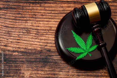 Obraz na płótnie Legal weed, decriminalized pot or felony conviction for possession of a schedule one drug concept theme with a marijuana leaf and a wooden gavel isolated on wood background with copy space w salonie