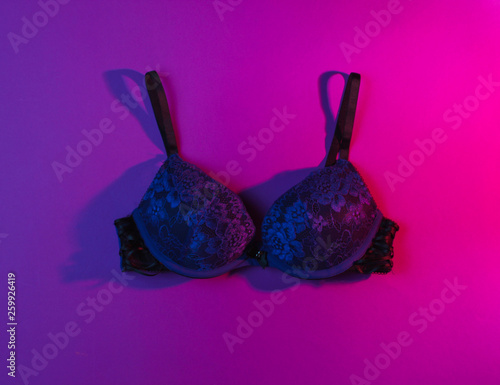 Erotic concept. Women's sexy bra, neon pink light. Top view
