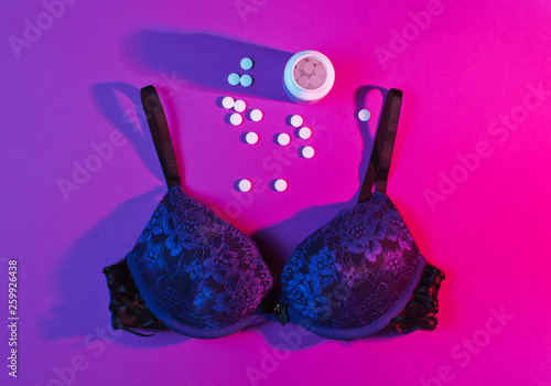 The concept of contraceptive sex. Female sexy bra, bottle of contraceptive pills, pink neon light, nightlife. Top view