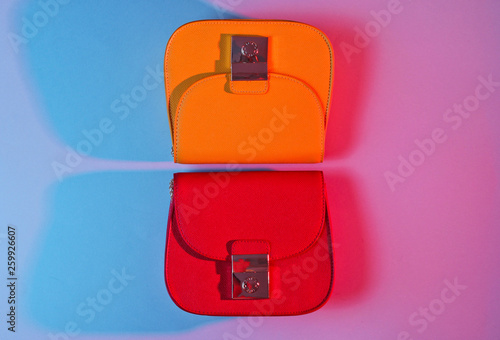 Minimalism fashion concept. Red and yellow mini bags with gradient red blue neon color light. Top view