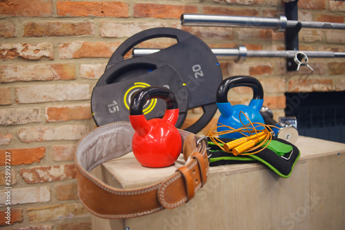 Functional training equipment. Kettlebell, dumbbels, barbell, jump rope on wooden box against the brick wall background. Workout concept
