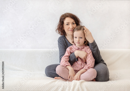 Tableau sur toile Young woman with her daughter are resting on the sofa.