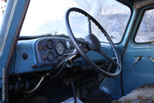 The interior of the cabin of the old truck: the cabin is mostly metal, large steering wheel and a simple dashboard. © Ihor95