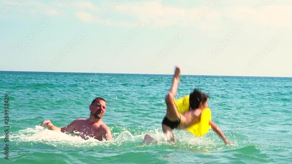 Dad throws up his son in an inflatable life jacket in the sea. Safety Concerns and Parental Care Concept. slow motion Dad throws up his son in an inflatable life jacket in the sea. Safety Concerns and Parental Care Concept. slow motion