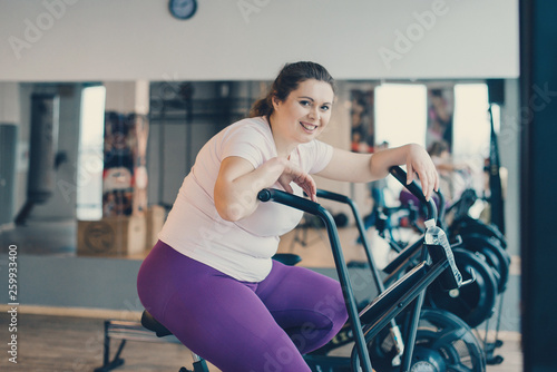 Fat woman sits tired on stationary bike