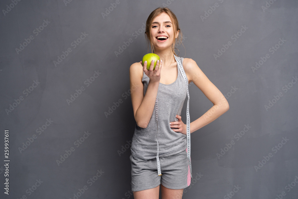 Healthy woman stands with tape measure and green apple. Healthy eating concept. Healthy woman stands with tape measure and green apple. Healthy eating concept.