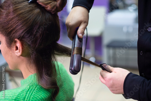 Woman hairdresser making hairstyle to girl in beauty salon