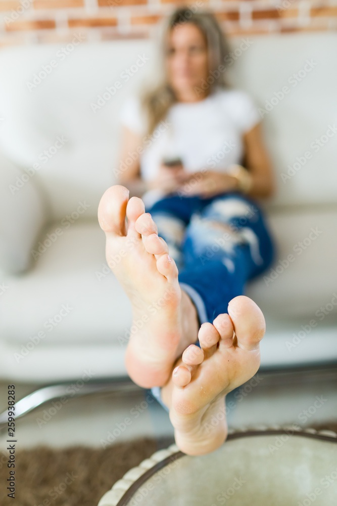 Fotografia do Stock: Woman feet in details in foreground, out of focus  woman in in blue jeans in background. | Adobe Stock