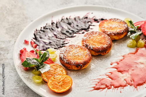 Cottage cheese pancakes, syrniki, curd fritters with fresh berries, grapes and orange.