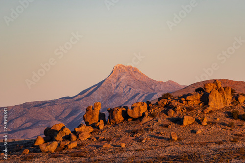 An iconic mountain peak bathes in golden hour light during sunset in the desert