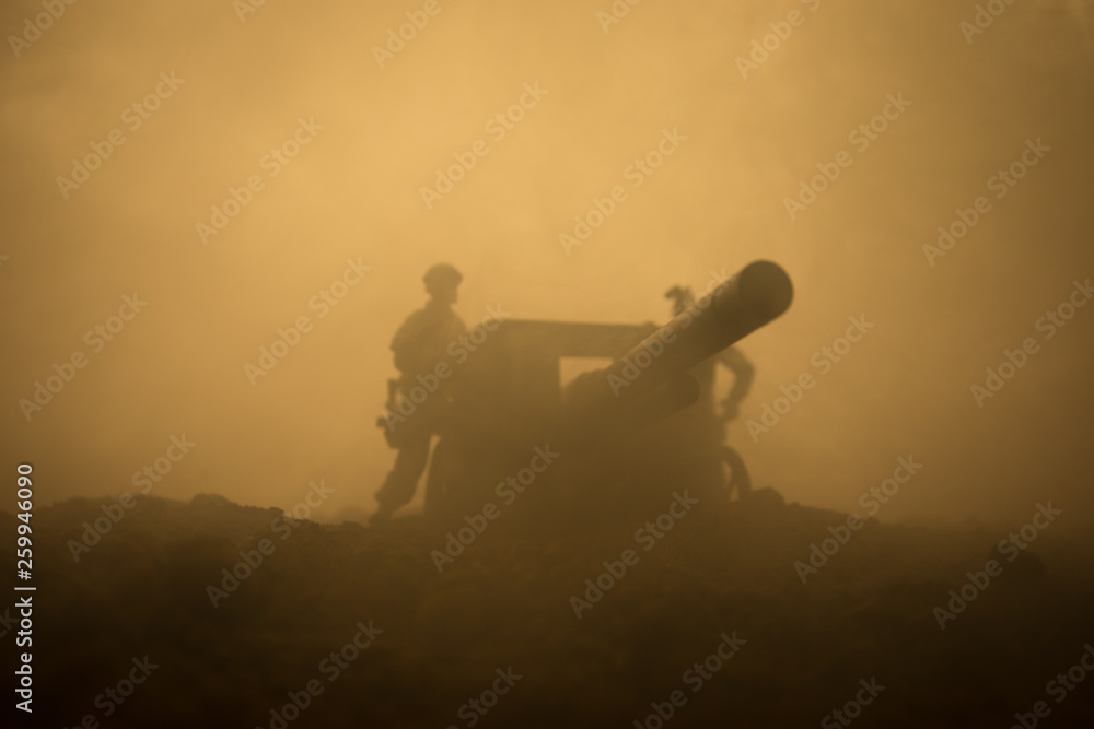 Fototapeta premium Battle scene. Silhouette of old field gun standing at field ready to fire. With colorful dark foggy background. Selective focus