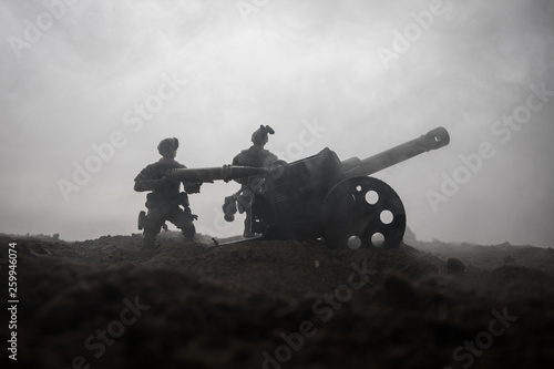Battle scene. Silhouette of old field gun standing at field ready to fire. With colorful dark foggy background. Selective focus photo