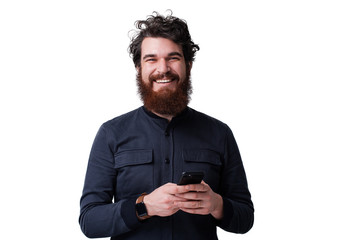 Portrait of excited satisfied with toothy beaming shiny smile  using smartphone for getting sending sms isolated on white background