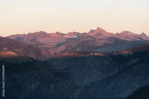 Distant controlled fire burns in the Sierra Nevada Mountains at dusk in Yosemite © Tabor Chichakly