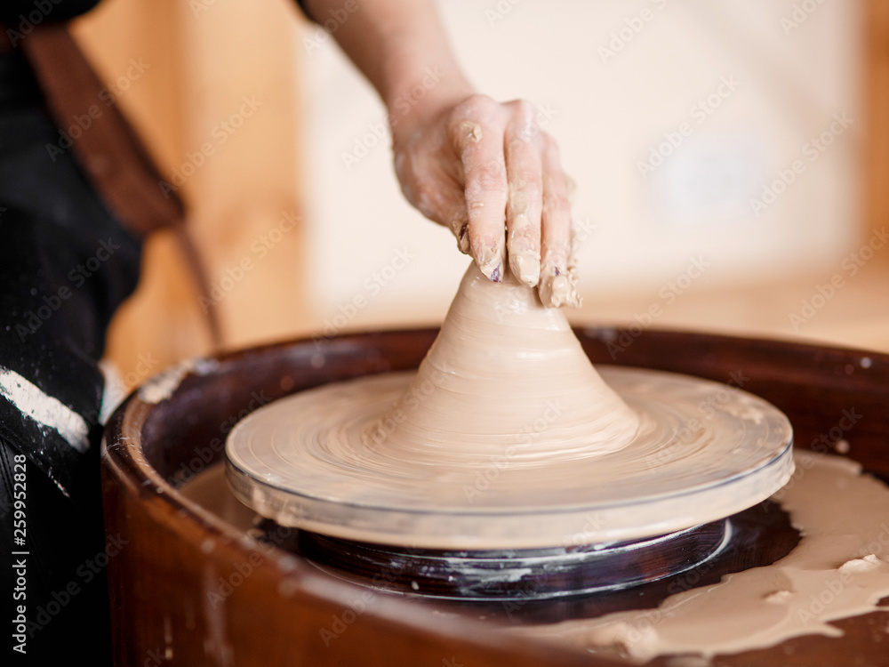 Hands sculpt new utensil on a pottery wheel