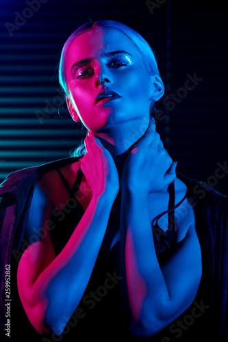 Fashion model blonde woman in colorful bright neon lights posing in studio.