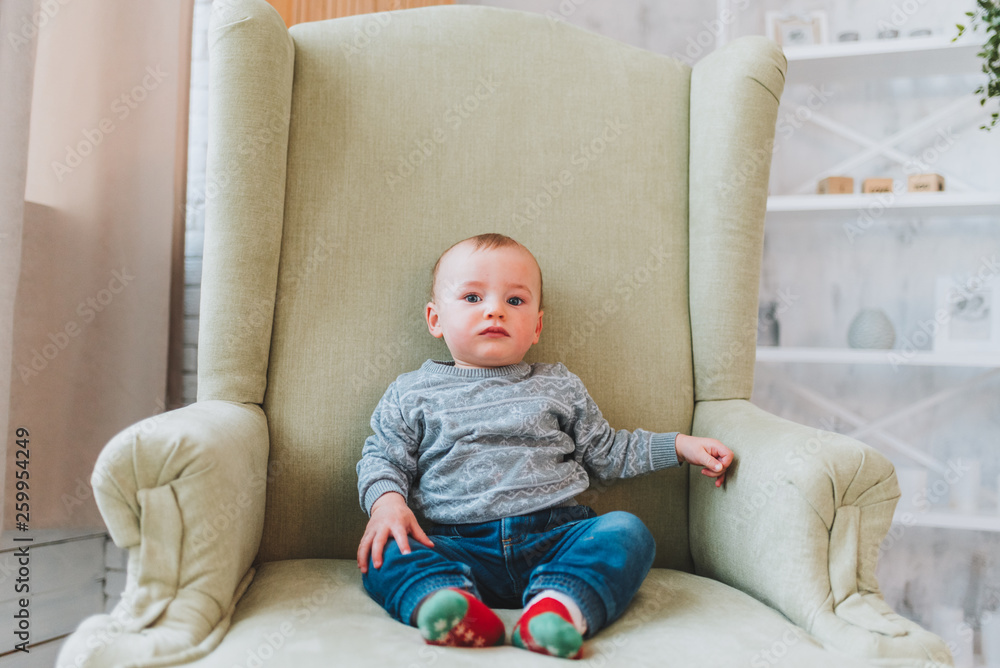 Cute little toddler boy sitting on big armchair Cute little toddler boy sitting on big armchair