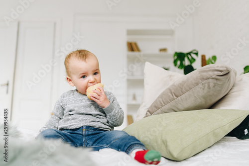 Very cute little toddler boy snacking. Baby or small child eating a piece of bread. Making funny silly face.