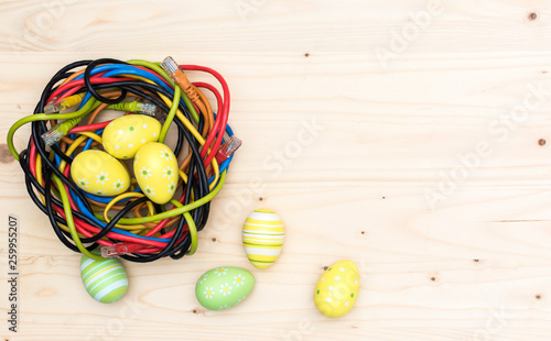 Easter eggs and nest of internet cables on wooden board