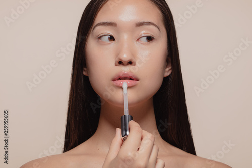 Woman applying transparent lip gloss