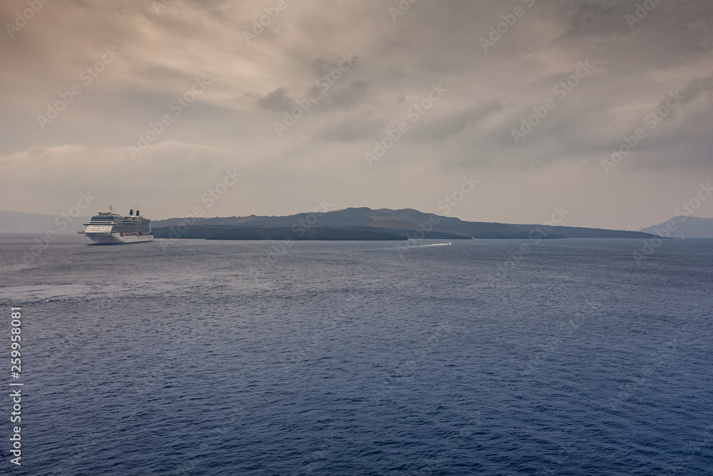 Panorama of Santorini on a cloudy day, with cruise ship waiting in the harbor