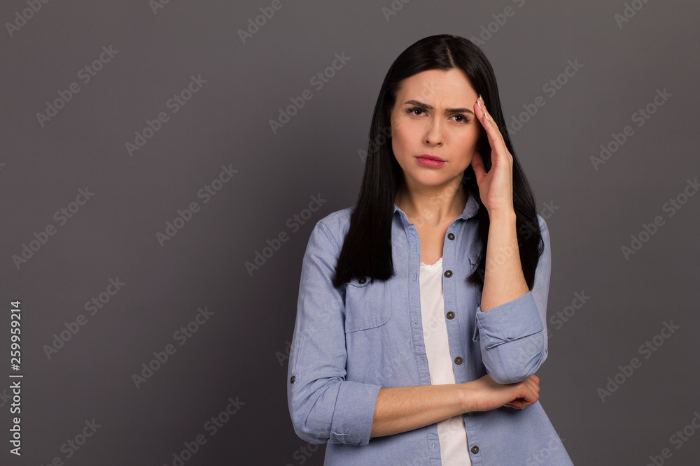 Closeup photo of lady after hardworking day touching temples endure terrible pain wearing denim shirt isolated on gray background Closeup photo of lady after hardworking day touching temples endure terrible pain wearing denim shirt isolated on gray background