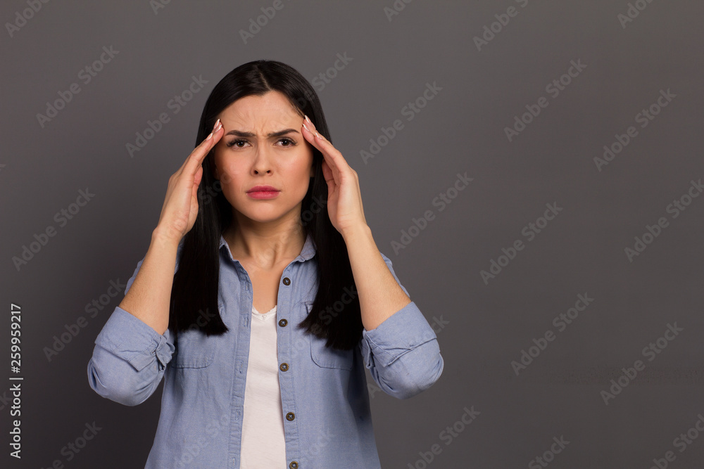 Closeup photo of lady after hardworking day touching temples endure terrible pain wearing denim shirt isolated on gray background Closeup photo of lady after hardworking day touching temples endure terrible pain wearing denim shirt isolated on gray background