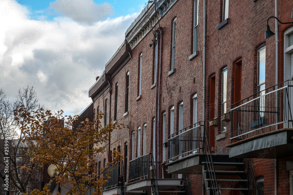 Fototapeta premium Facades of traditional North American residential buildings, red brick houses, taken in the center of Montreal, the second biggest city of Canada, and a business hub of Canada