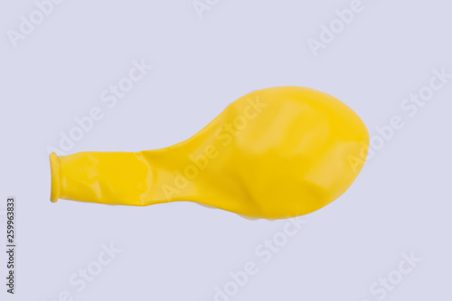 Yellow deflated balloon on white background. New airless balloon, horizontal image. Minimal concept.
