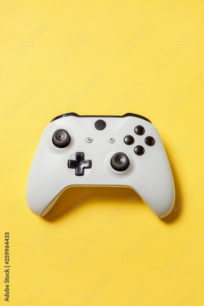 White joystick gamepad, game console on yellow colourful trendy modern fashion pin-up background. Computer gaming competition videogame control confrontation concept. Cyberspace symbol White joystick gamepad, game console on yellow colourful trendy modern fashion pin-up background. Computer gaming competition videogame control confrontation concept. Cyberspace symbol
