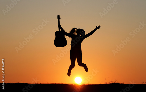 Silhouette of a guitar player at sunset, girl guitarist, silhouette of a guitar, music, girl jumping with a guitar