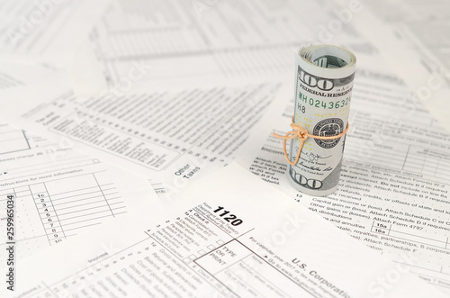 1120 U.S. Corporation income tax return form with roll of american dollar banknotes photo