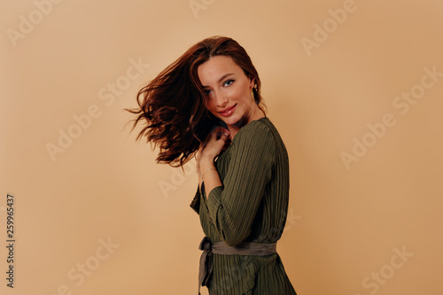 Attractive woman with natural beauty has fun during photoshoot in studio against beige background 