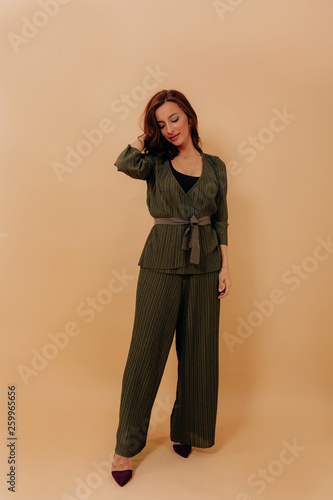 Full-lenght photo of elegant stylish woman wearing stylish pantsuit against beige background