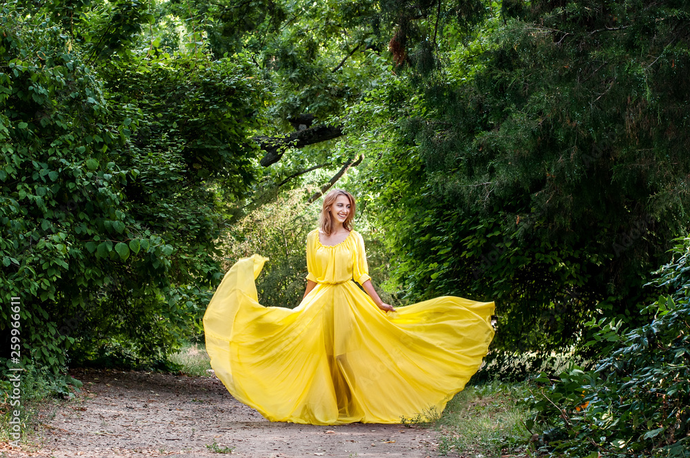 Incredible beautiful dancer in a long yellow dress. Fashion and beauty dancer. A girl in a yellow dress is dancing in a flowered park. Incredible beautiful dancer in a long yellow dress. Fashion and beauty dancer. A girl in a yellow dress is dancing in a flowered park.
