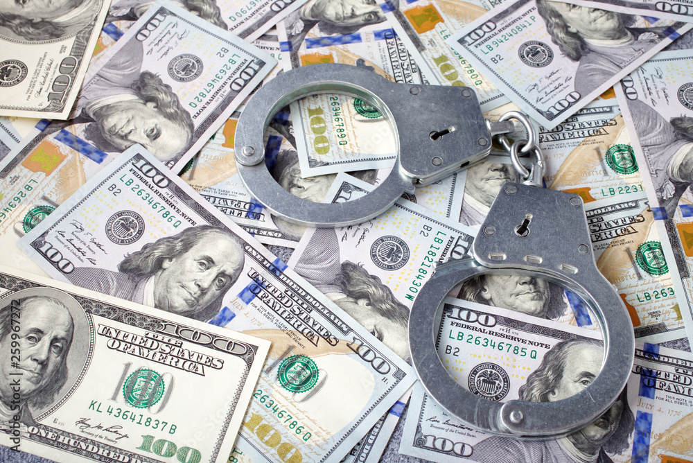 Handcuffs on dollars background. Criminal money concept Handcuffs on dollars background. Criminal money concept