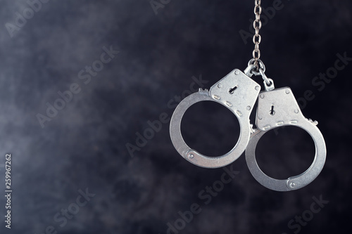 Photographie Handcuffs hanging against a dark background with copy space