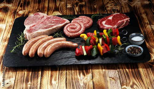 Assorted delicious raw meat with vegetable on a barbecue with t-bone steak, sausages and meat Skewers.