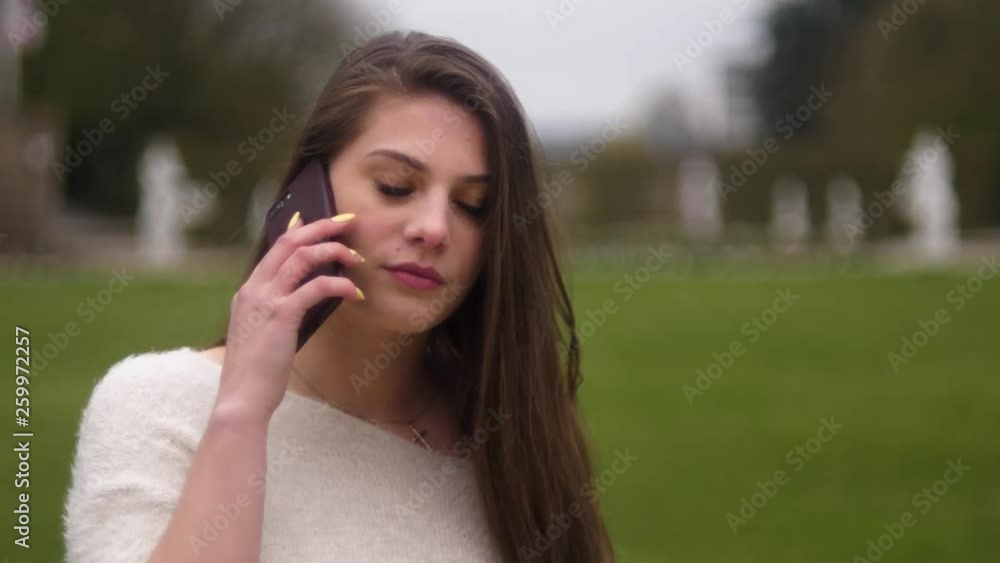 Young attractive woman is on the phone in the park. Young attractive woman is on the phone in the park.