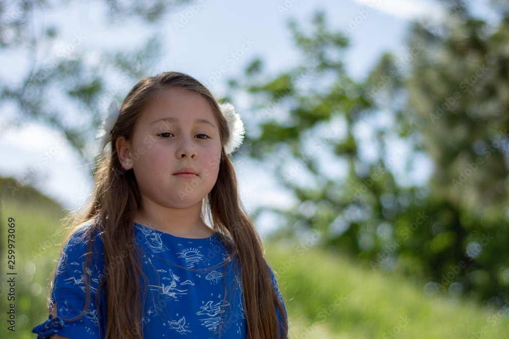 Serious and Thoughtful Little Girl in Blue Dress in front of golden field at Park Serious and Thoughtful Little Girl in Blue Dress in front of golden field at Park