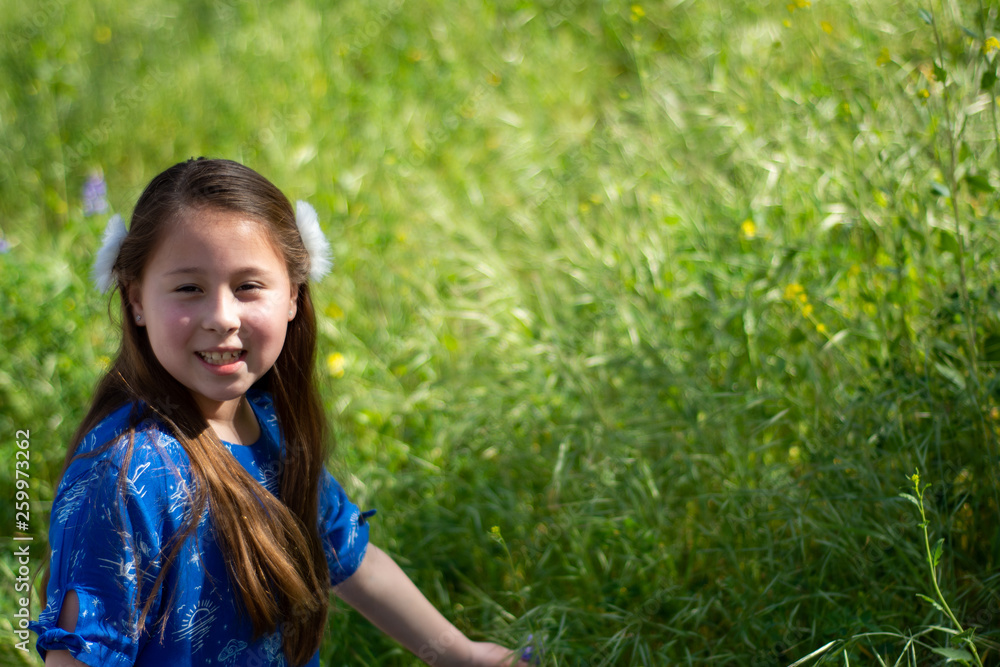 Little Girl in Blue Dress Smiling in Front of Field with Flowers Little Girl in Blue Dress Smiling in Front of Field with Flowers