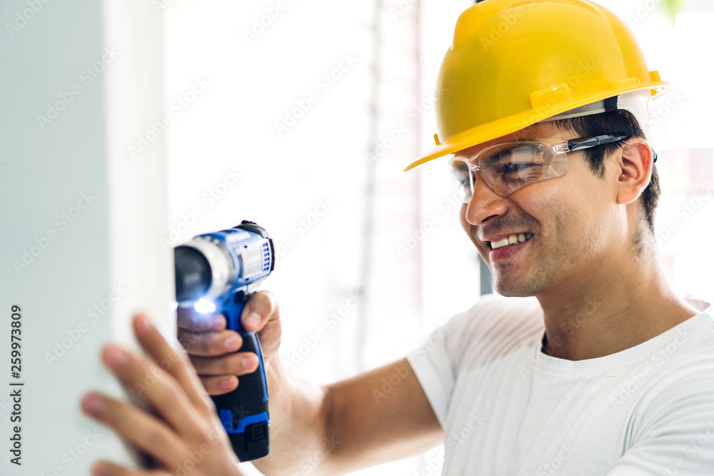 Young construction worker working with screwdriver to drill in a house entrance Young construction worker working with screwdriver to drill in a house entrance