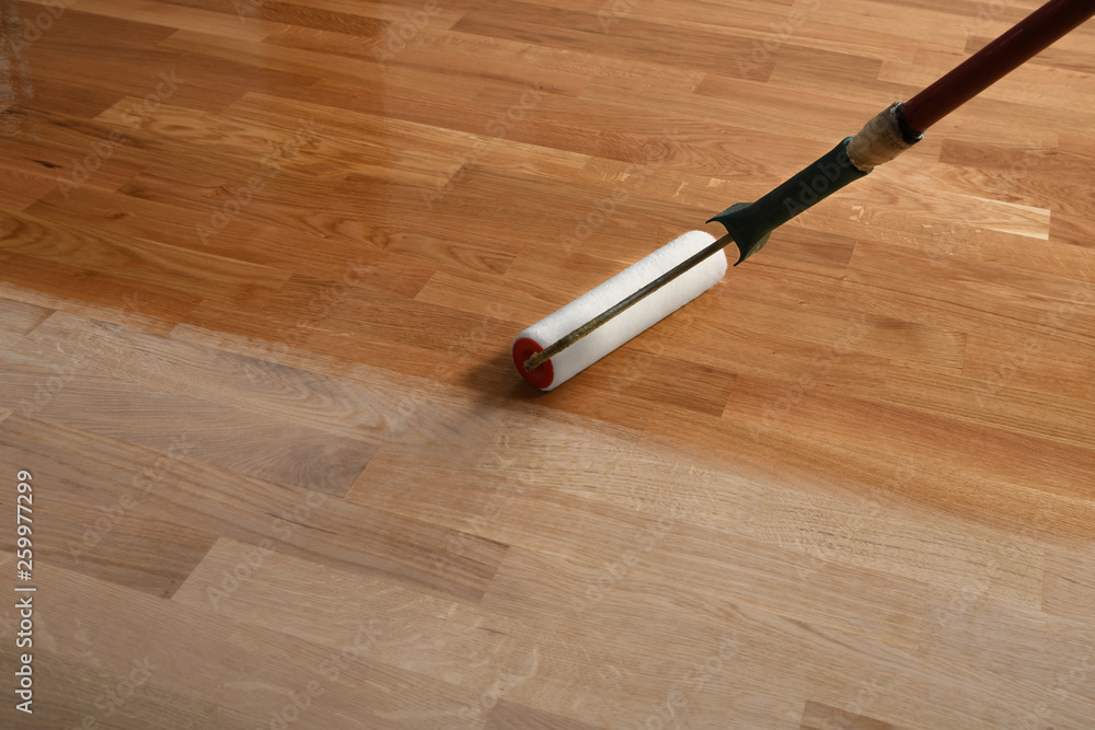Lacquering wood floors. Worker uses a roller to coating floors. - obrazy, fototapety, plakaty 