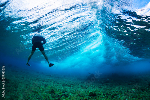 Underwater photographer floats in the wave with big wave breaking in the frame