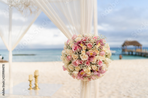 Blumenstrauss mit pastellfarbenen Rosen einer Hochzeitsdekoration am Strand am Strand mit Meer im HIntergrund