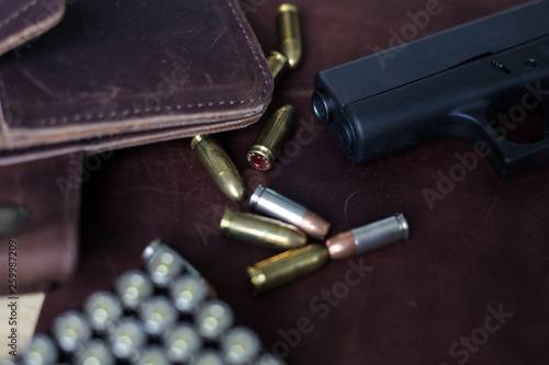 9mm Sub compact everday carry modern gun with bullet on leather background