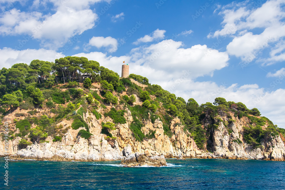 Costa Brava rocky coast with ancient tower on tall shore in Lloret de Mar, Spain. Mediterranean sea landscape
