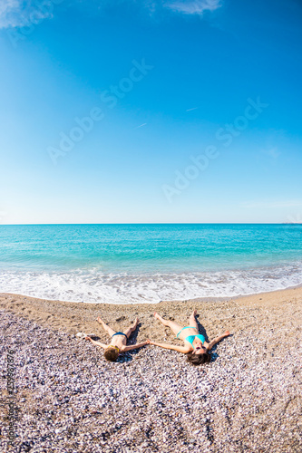 The boy with his mother sunbathe on the beach.