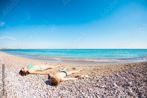 The boy with his mother sunbathe on the beach.